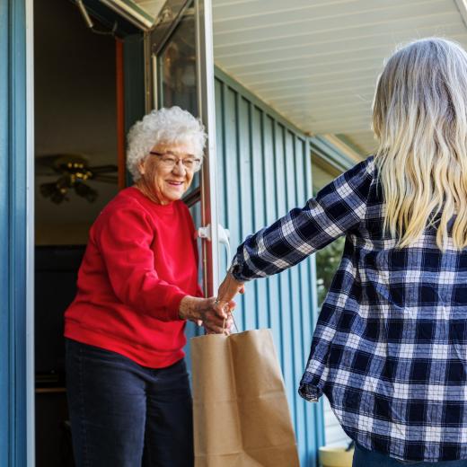 Volunteer handing a bag of food to a senior citizen