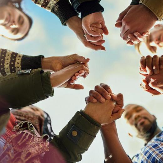 People in a circle looking down and holding hands