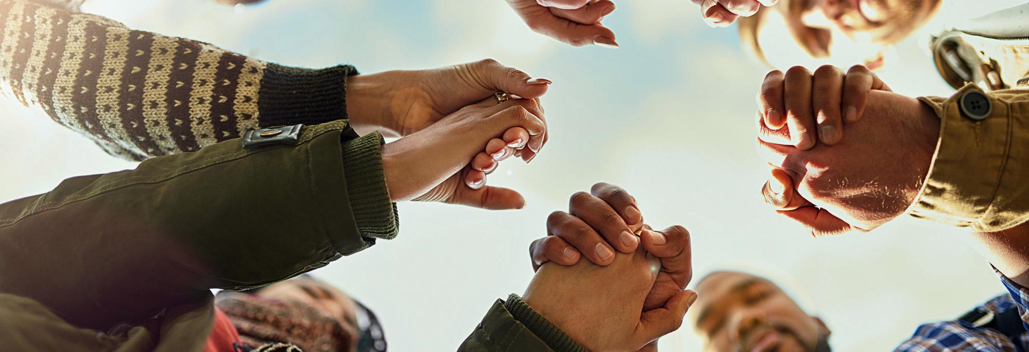 People in a circle looking down and holding hands