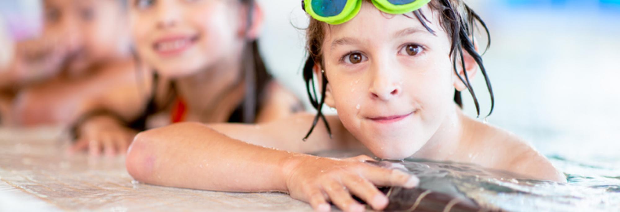 Smiling children along the side of a pool