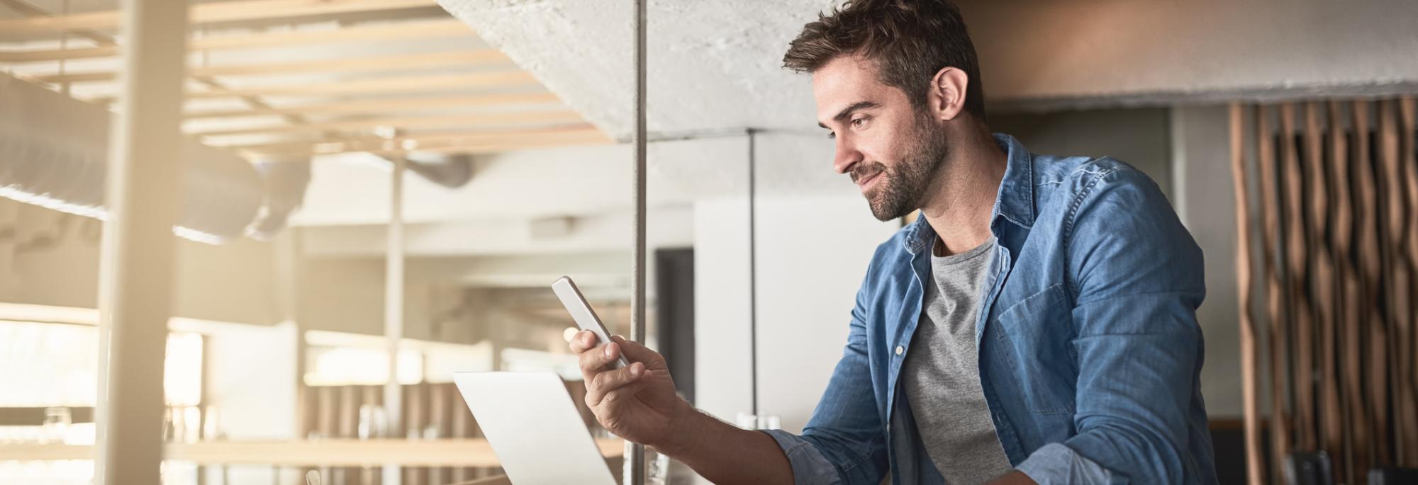 Man working on laptop and looking at mobile phone