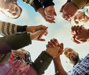 People in a circle looking down and holding hands