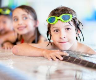 Smiling children along the side of a pool